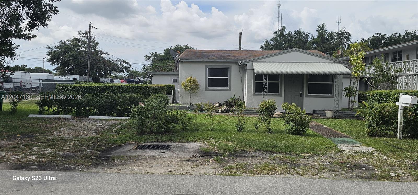 A single-story house with a gray exterior, metal awning, and a front lawn — 6010 SW 33rd St, Miramar FL 33023, MIRAMAR, FL