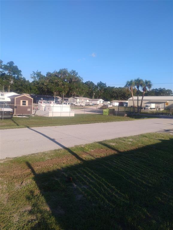 A grassy, vacant residential lot features a mailbox in the foreground and trees in the background — 587 MARSHBURN DRIVE, BRONSON, FL