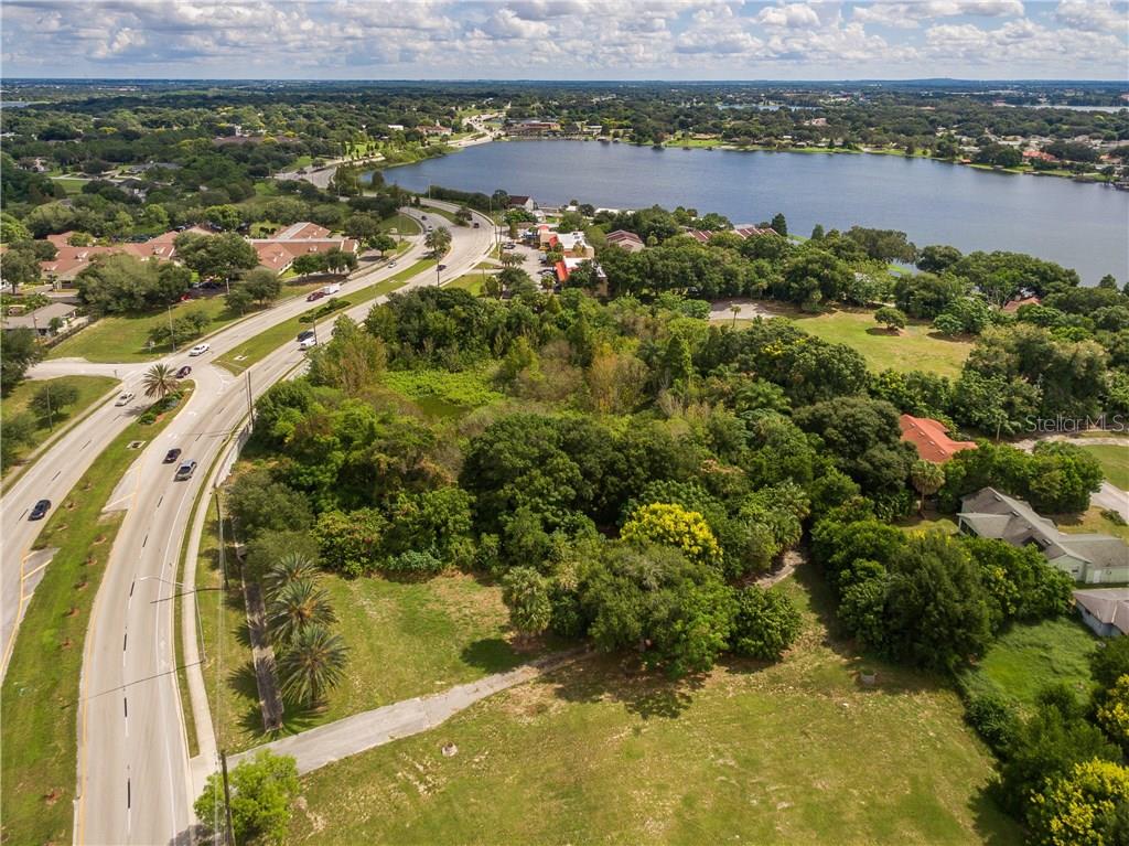 An aerial view shows a grassy lot next to a road and a large lake — 1101 CYPRESS GARDENS BOULEVARD, WINTER HAVEN, FL