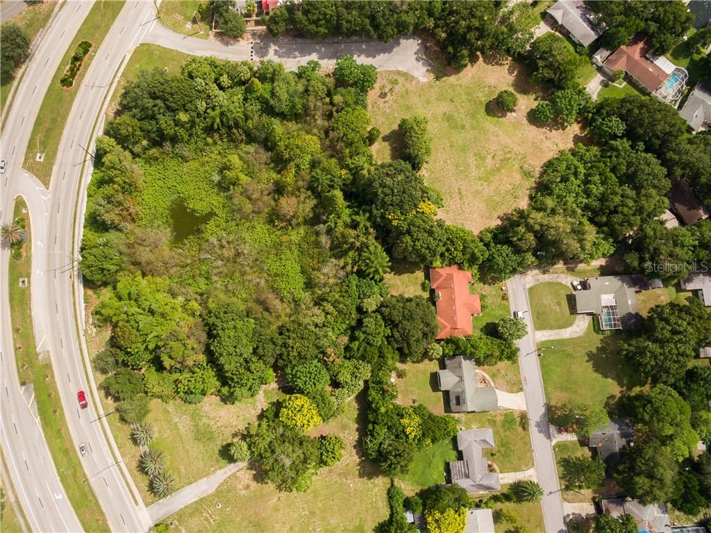 An aerial view shows a large, wooded lot with a pond next to a road — 1101 CYPRESS GARDENS BOULEVARD, WINTER HAVEN, FL