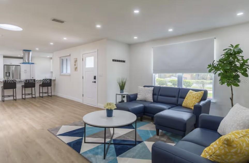 A living room with a blue sectional sofa, geometric rug, and an open kitchen area — 8622 Baylor Cir, Orlando FL 32817, ORLANDO, FL