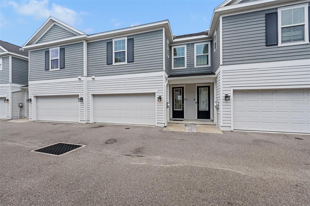 A multi-unit residential building with gray siding, white trim, and three garage doors — 6615 S MANHATTAN AVENUE UNIT 3, TAMPA, FL