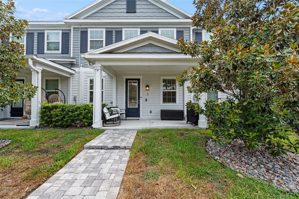 A paved walkway leads to the covered front porch of a two-story gray townhouse — 6615 S MANHATTAN AVENUE UNIT 3, TAMPA, FL