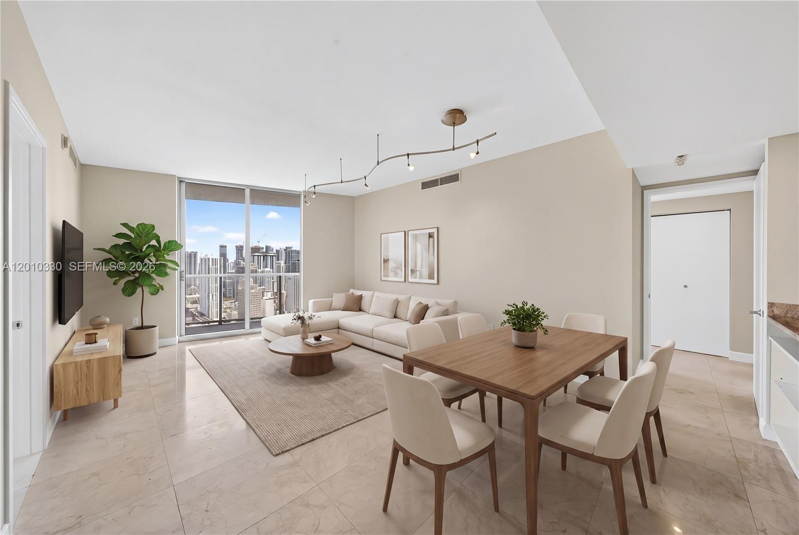 A modern living and dining area features tile floors, a sectional sofa, and city views — 185 SW 7th St # 4209, Miami FL 33130, MIAMI, FL