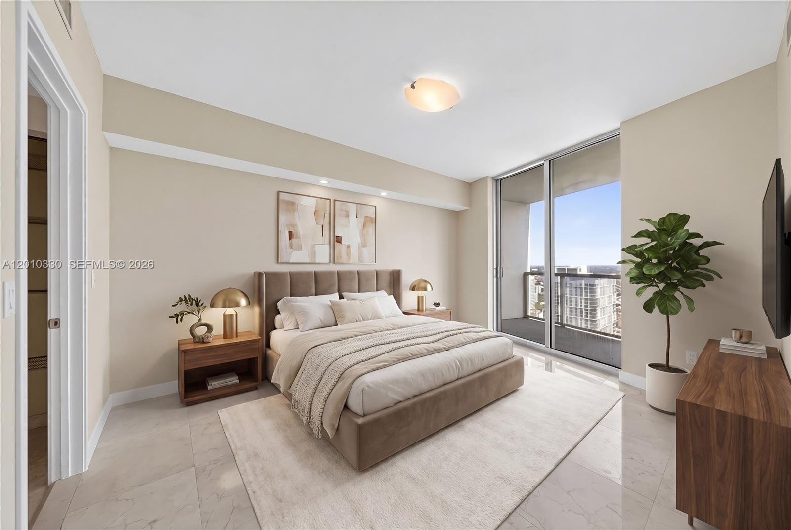 A modern bedroom features a tufted bed, neutral decor, and floor-to-ceiling windows with city views — 185 SW 7th St # 4209, Miami FL 33130, MIAMI, FL