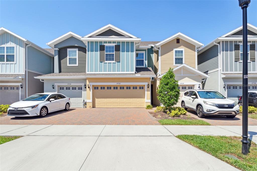 A row of multi-story townhomes with garages and paved driveways under a clear blue sky — 5732 SKYTOP DRIVE, LITHIA, FL