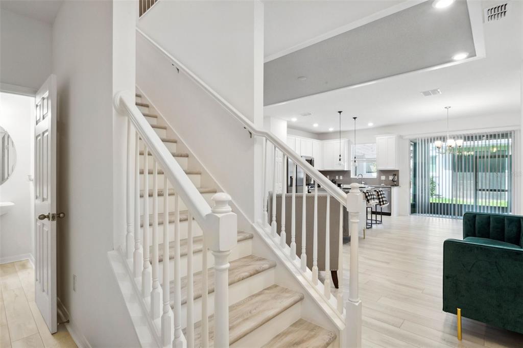 A staircase with white railings leads to an upper level overlooking an open-concept kitchen area — 5732 SKYTOP DRIVE, LITHIA, FL