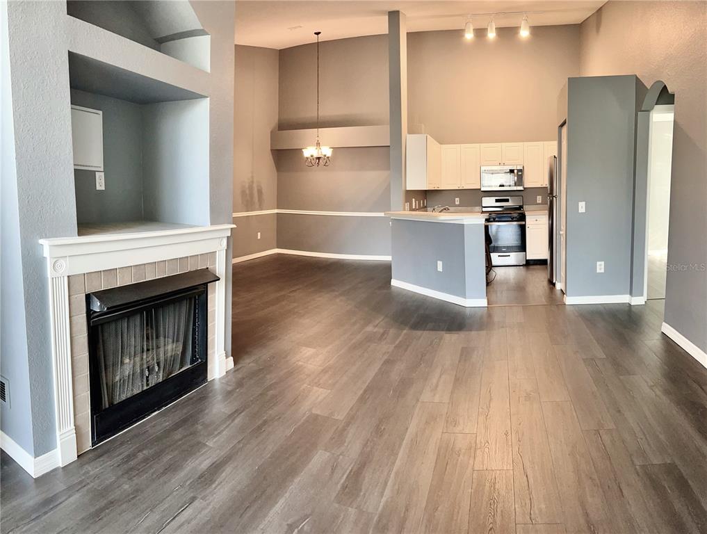 A living room with a fireplace and wood-look flooring opens to a kitchen and dining area — 3361 S KIRKMAN ROAD UNIT 821, ORLANDO, FL