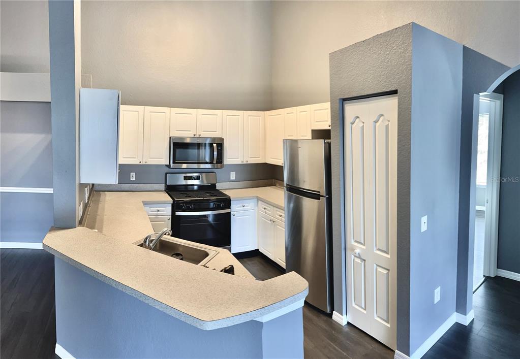 A kitchen features white cabinets, stainless steel appliances, and a peninsula with a sink — 3361 S KIRKMAN ROAD UNIT 821, ORLANDO, FL