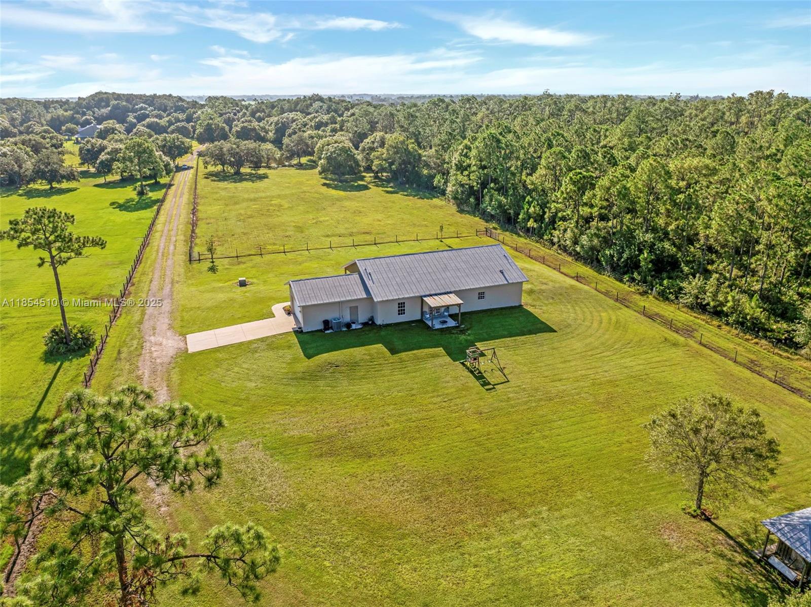 An aerial view shows a single-story house with a metal roof on a large lot — 99 TRADER RD, La Belle FL 33935, LA BELLE, FL