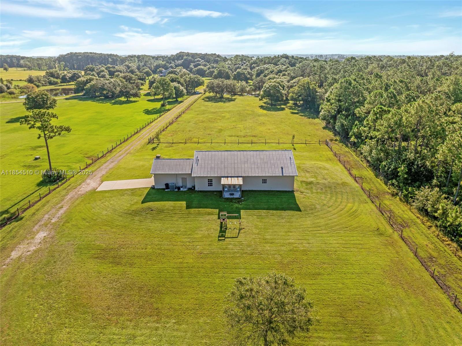An aerial view shows a single-story house with a metal roof on a large grassy lot — 99 TRADER RD, La Belle FL 33935, LA BELLE, FL