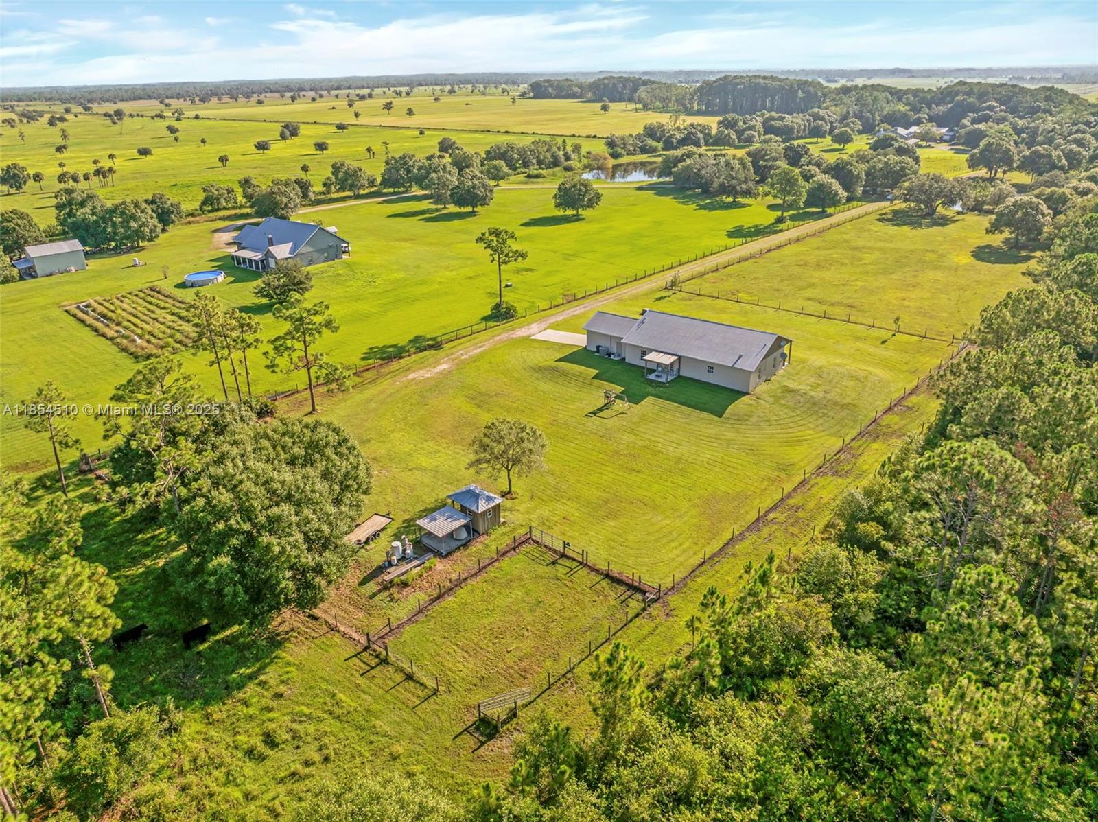 An aerial view shows a rural property with two houses, fenced pastures, and scattered trees — 99 TRADER RD, La Belle FL 33935, LA BELLE, FL