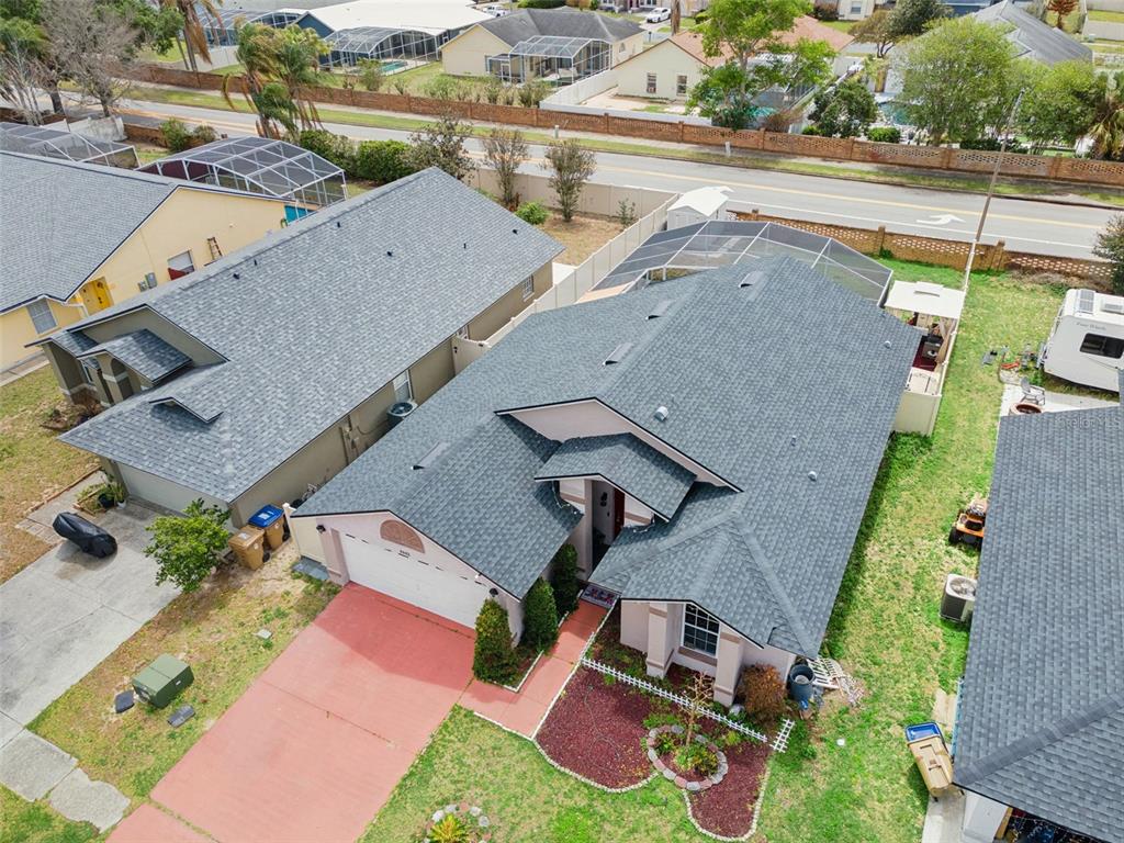 An aerial view shows a suburban house with a gray shingled roof and driveway — 8602 WELLINGTON LOOP, KISSIMMEE, FL