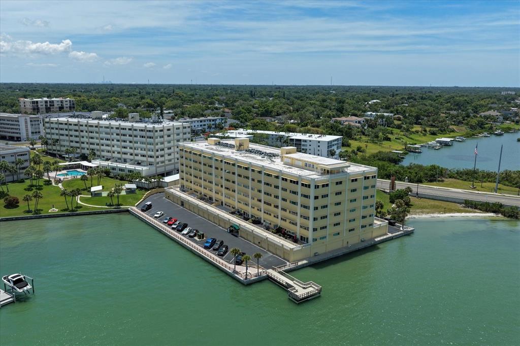 An aerial view of a multi-story apartment building situated on a waterfront peninsula — 100 BLUFF VIEW DRIVE UNIT 506C, BELLEAIR BLUFFS, FL