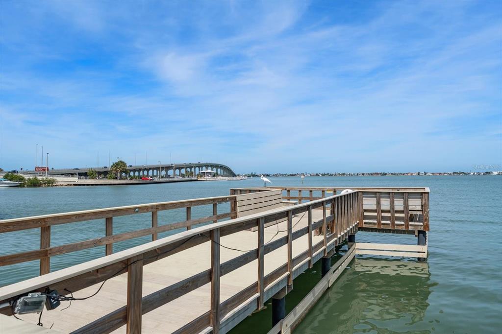 A wooden pier extends over the water toward a bridge under a blue sky — 100 BLUFF VIEW DRIVE UNIT 506C, BELLEAIR BLUFFS, FL