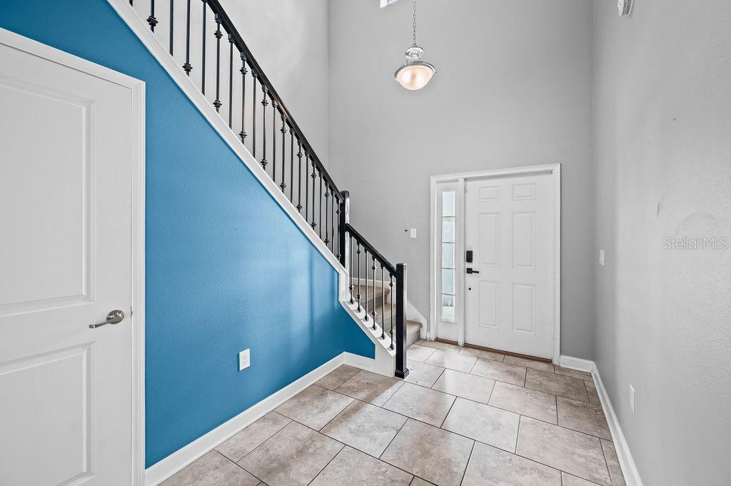 An entryway features a blue accent wall, a staircase with black railings, and tile flooring — 4538 CORTLAND DRIVE, DAVENPORT, FL