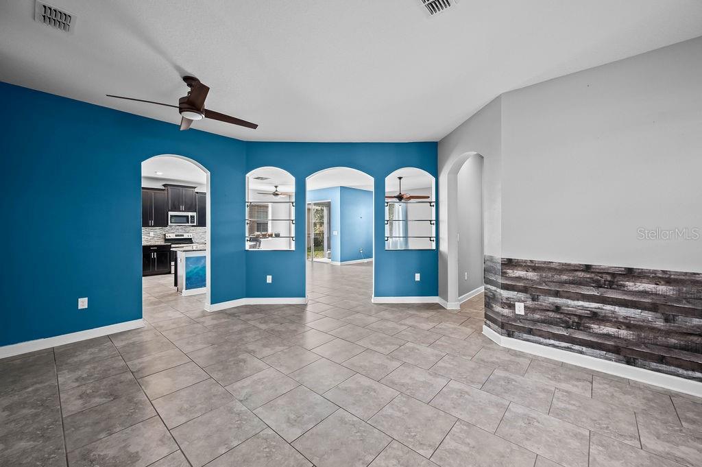 A room with blue walls, arched cutouts, tile flooring, and a wood-paneled accent wall — 4538 CORTLAND DRIVE, DAVENPORT, FL