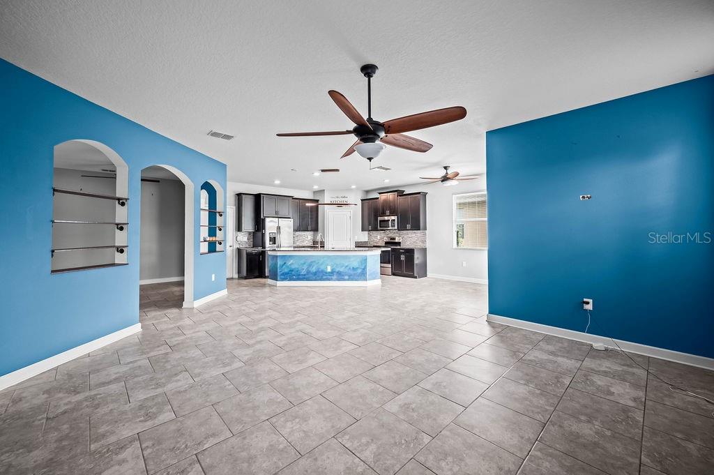 An open-concept kitchen and living area features blue accent walls and tile flooring — 4538 CORTLAND DRIVE, DAVENPORT, FL