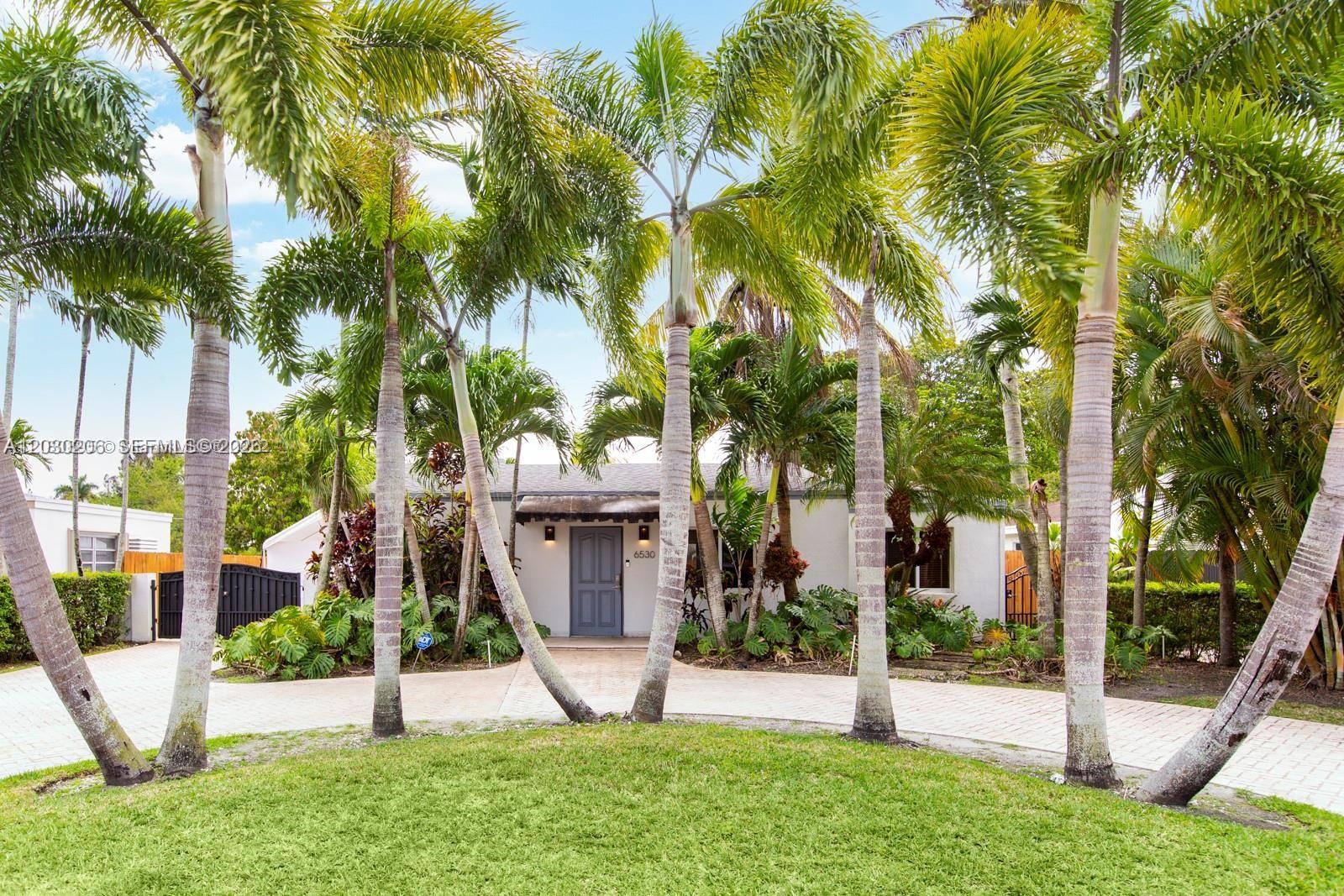 A single-story house with a paved driveway is surrounded by many tall palm trees — 6530 SW 43rd St, Miami FL 33155, MIAMI, FL