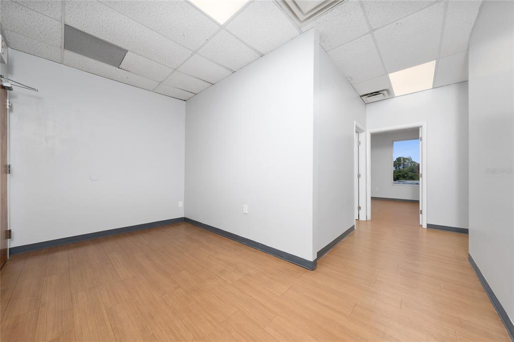 An empty office space features light wood-look flooring, white walls, and a drop ceiling — 7200 LAKE ELLENOR DRIVE UNIT 130, ORLANDO, FL