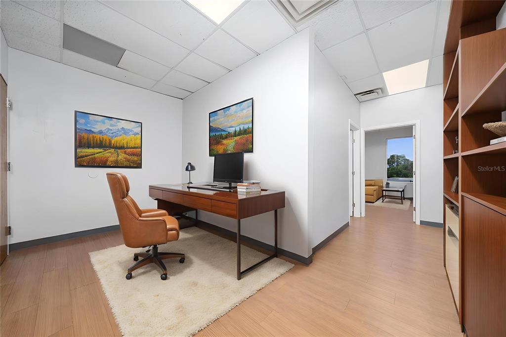 A modern office features a wooden desk, leather chair, area rug, and built-in shelving — 7200 LAKE ELLENOR DRIVE UNIT 130, ORLANDO, FL