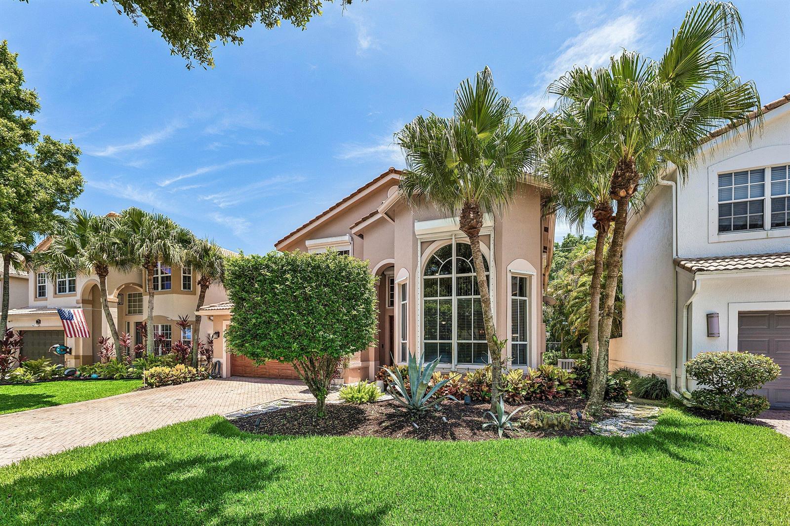 A tan two-story house with a brick driveway, palm trees, and a large arched window — 4858 S Classical Boulevard, Delray Beach FL 33445, DELRAY BEACH, FL