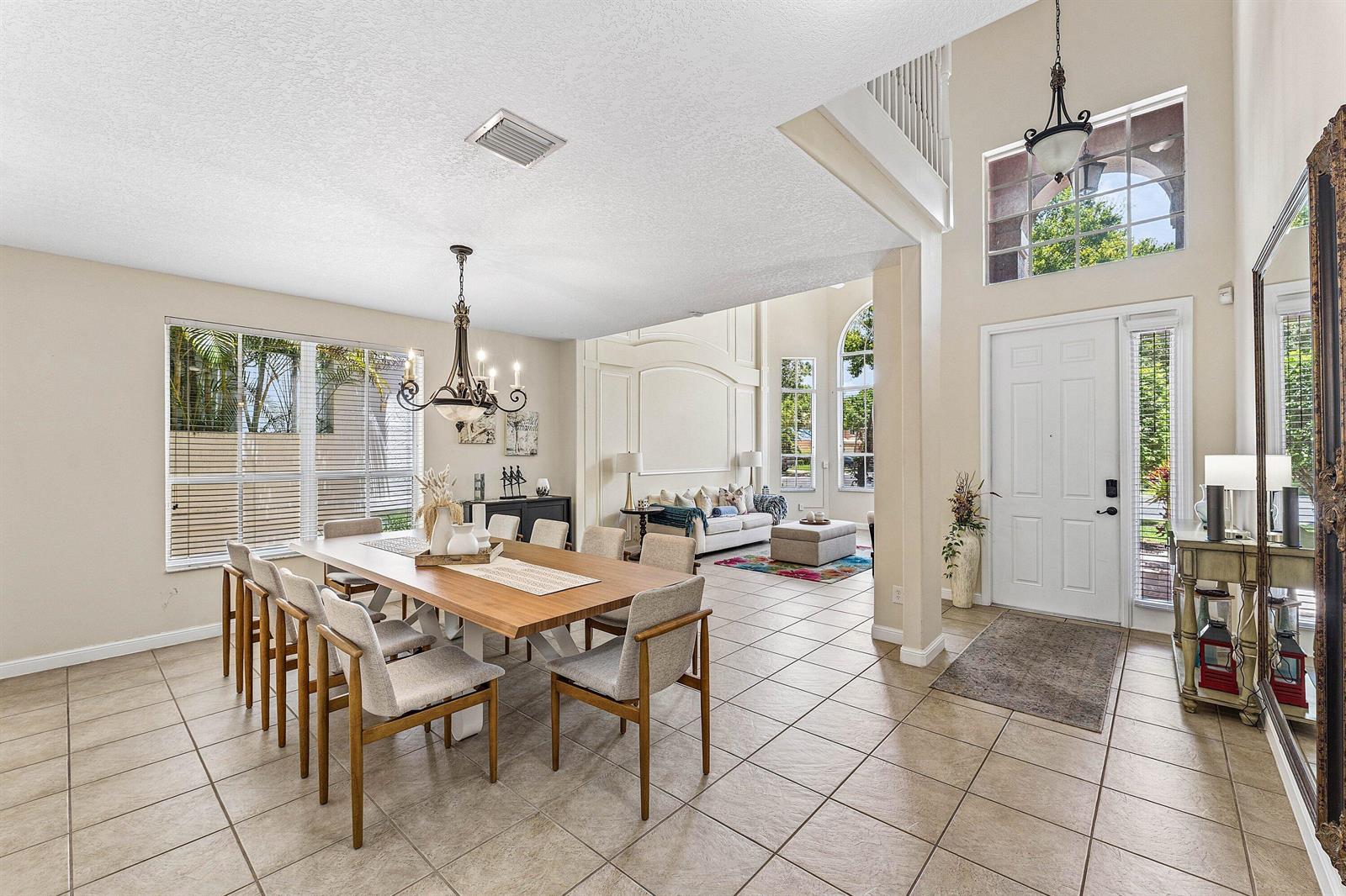 A dining area and entryway feature tile floors, a wooden table, and high vaulted ceilings — 4858 S Classical Boulevard, Delray Beach FL 33445, DELRAY BEACH, FL