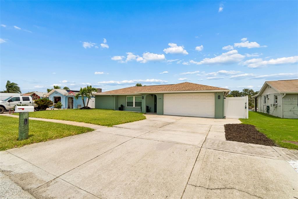A single-story house with a green exterior, a two-car garage, and a concrete driveway — 1166 CHANCELLOR DRIVE, HOLIDAY, FL