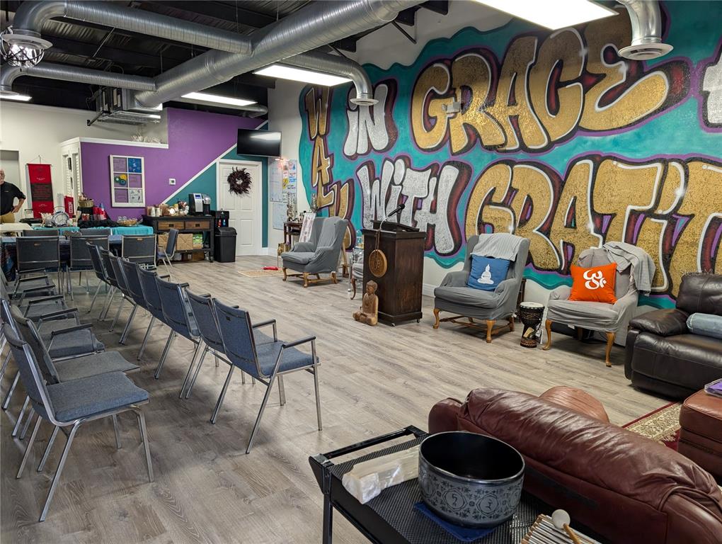 A room with rows of chairs, armchairs, a podium, and a large graffiti-style wall mural — 7015 N MANHATTAN AVENUE, TAMPA, FL