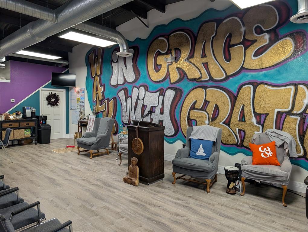 A room with wood-look flooring, a large graffiti-style wall mural, and several armchairs — 7015 N MANHATTAN AVENUE, TAMPA, FL