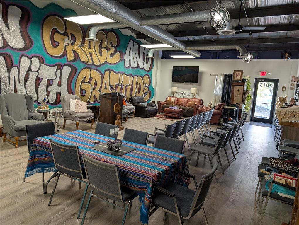 A large room features a mural, rows of chairs, a dining table, and lounge seating — 7015 N MANHATTAN AVENUE, TAMPA, FL