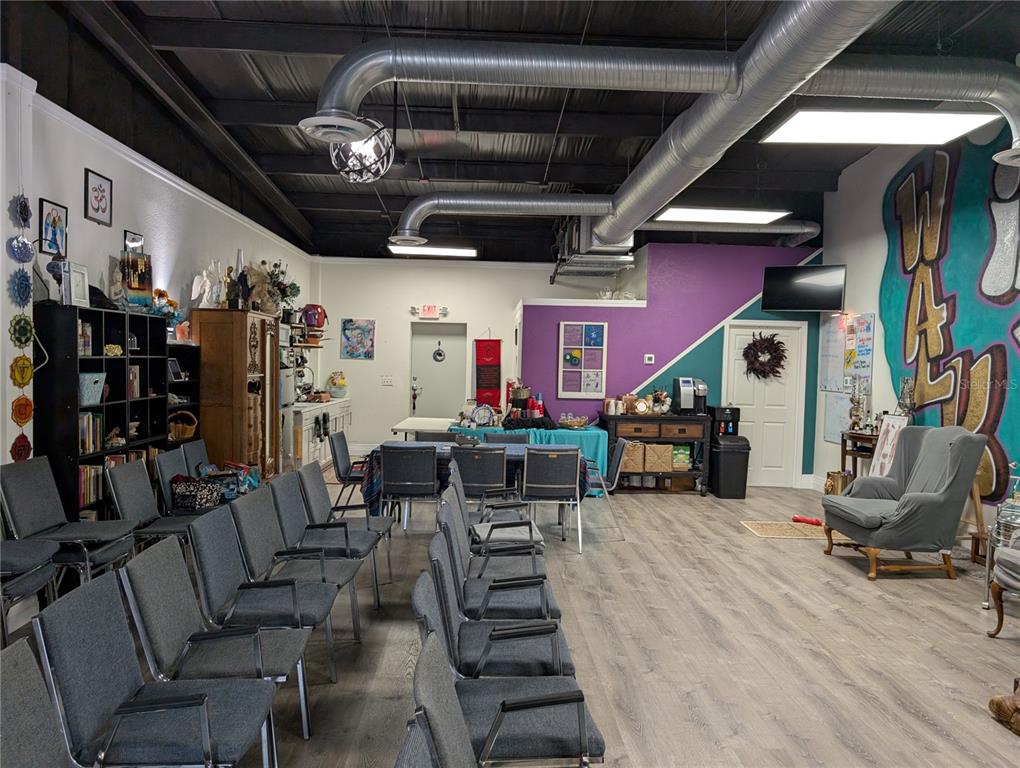 A room with rows of chairs, a table, a purple wall, and exposed ceiling ducts — 7015 N MANHATTAN AVENUE, TAMPA, FL