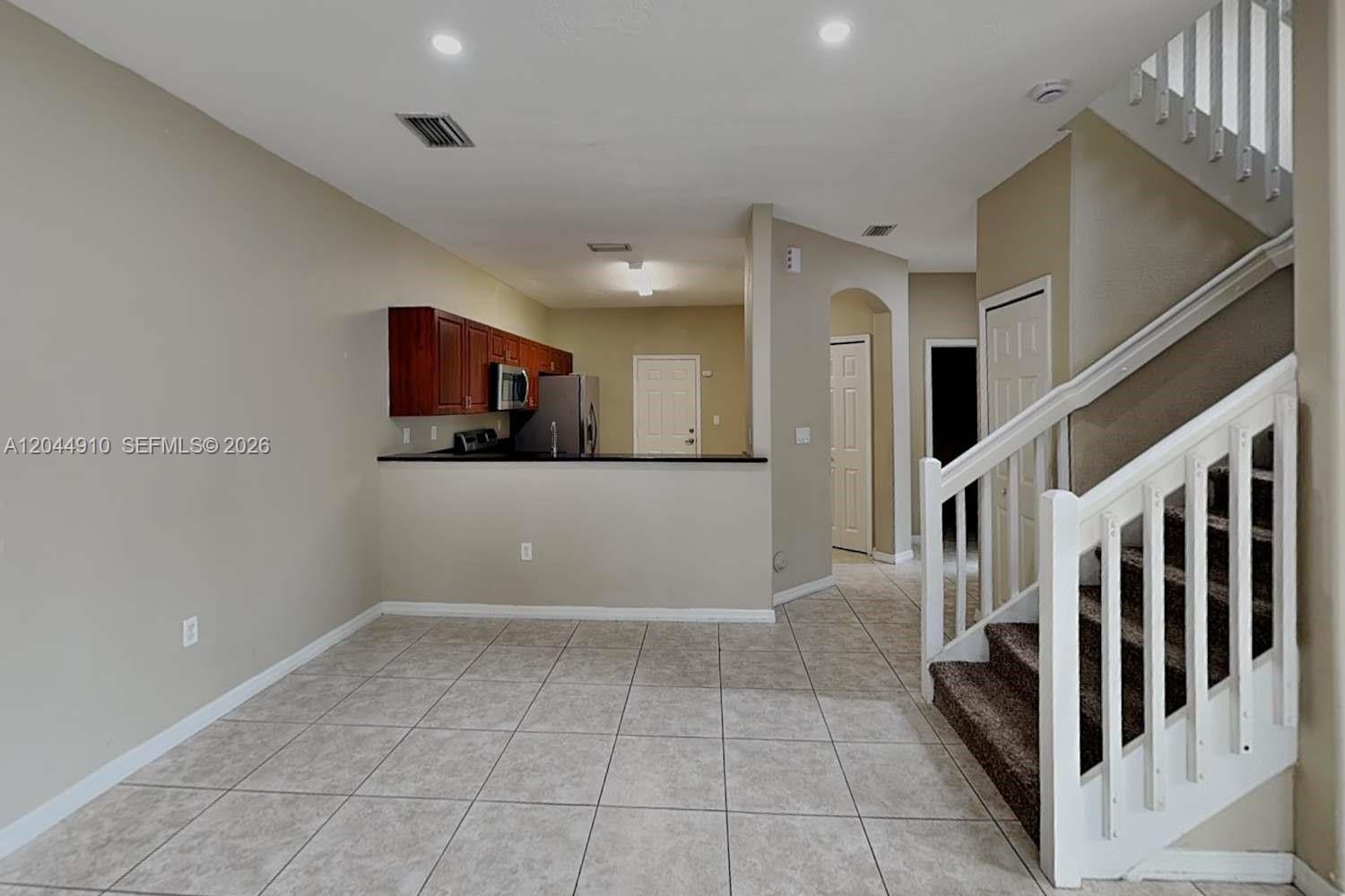 This interior view shows a tiled living area with a staircase and an open kitchen — MIAMI, FL