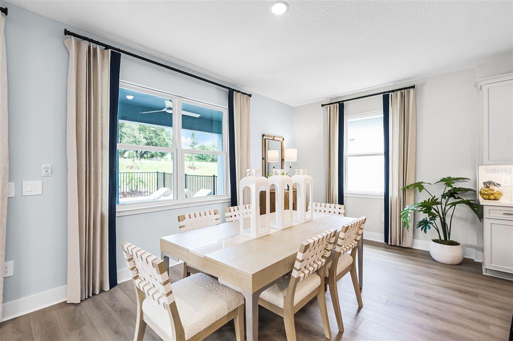 A dining room features a light wood table, woven chairs, and floor-to-ceiling curtains — 714 EMERALD GROVE DRIVE, APOPKA, FL