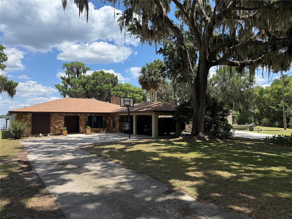 A single-story stone house with a carport, a basketball hoop, and large mossy oak trees — 4232 COUNTY ROAD 400, LAKE PANASOFFKEE, FL