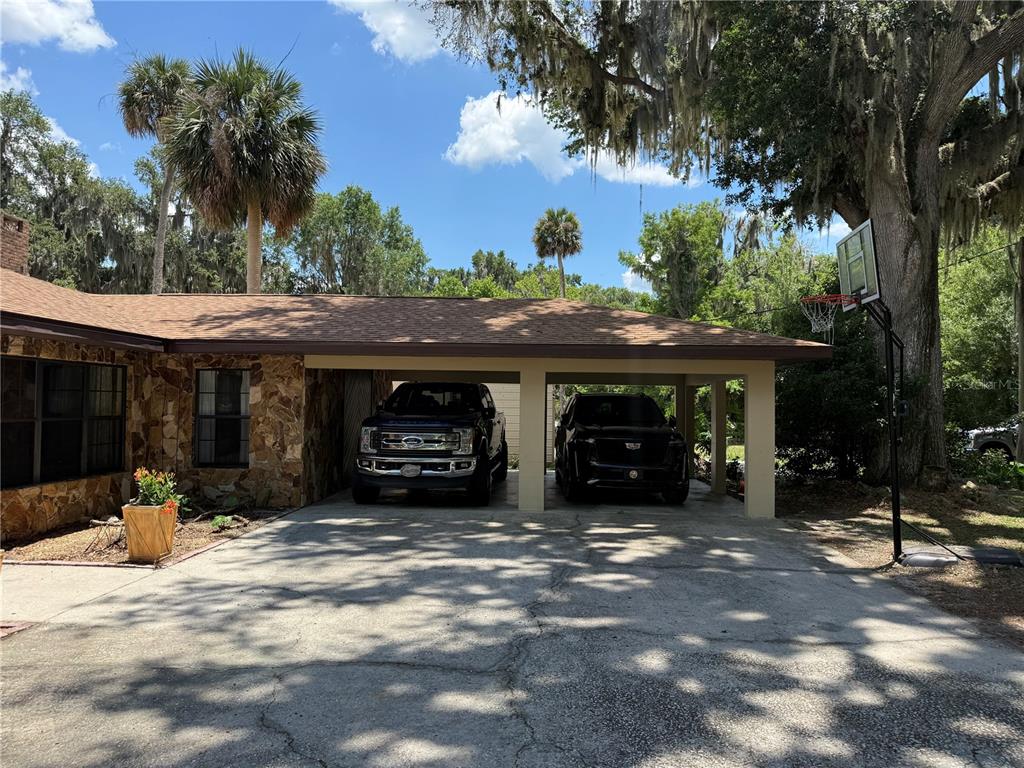 A stone-faced house features a two-car carport and a basketball hoop on the driveway — 4232 COUNTY ROAD 400, LAKE PANASOFFKEE, FL