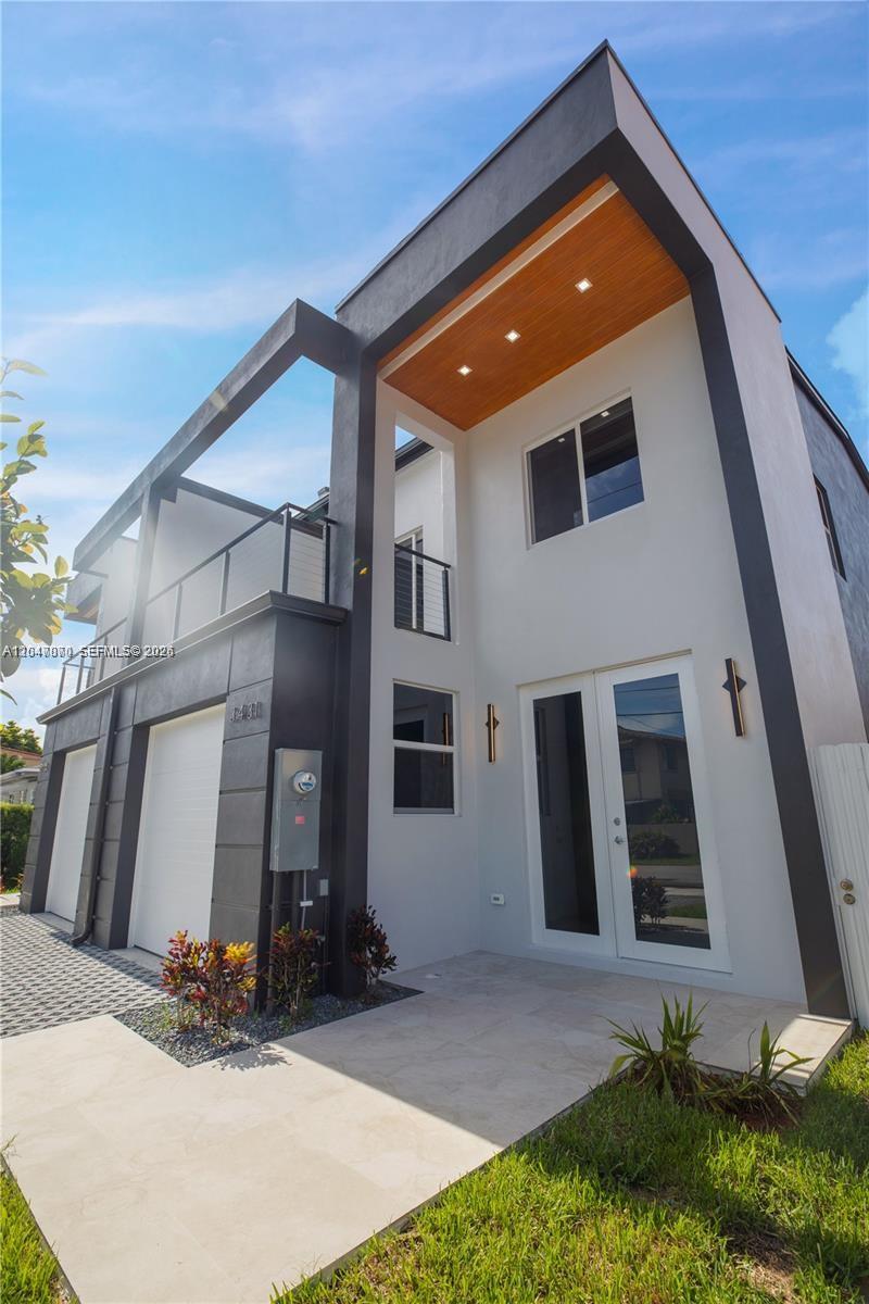 A modern two-story house exterior features a white facade, dark trim, and a wood-paneled entryway — 3431 SW 16th Ter # 1, Miami FL 33145, MIAMI, FL