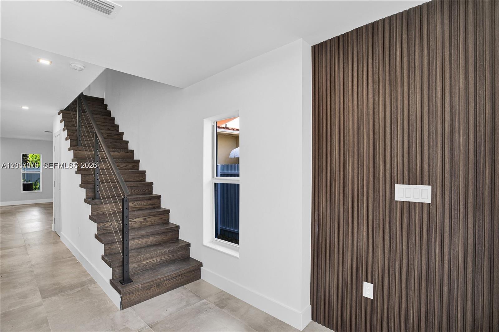 A staircase with dark wood treads and a cable railing sits beside a slatted wall — 3431 SW 16th Ter # 1, Miami FL 33145, MIAMI, FL