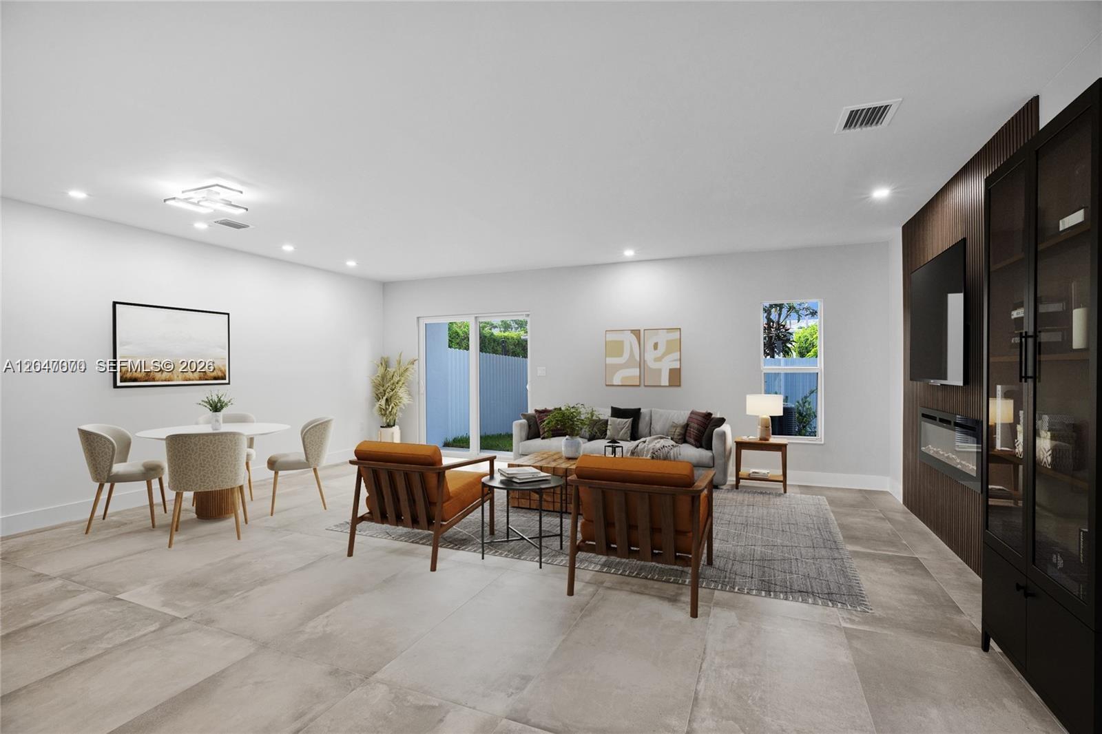 This living and dining area features large floor tiles, a wood-paneled accent wall, and furniture — 3431 SW 16th Ter # 1, Miami FL 33145, MIAMI, FL