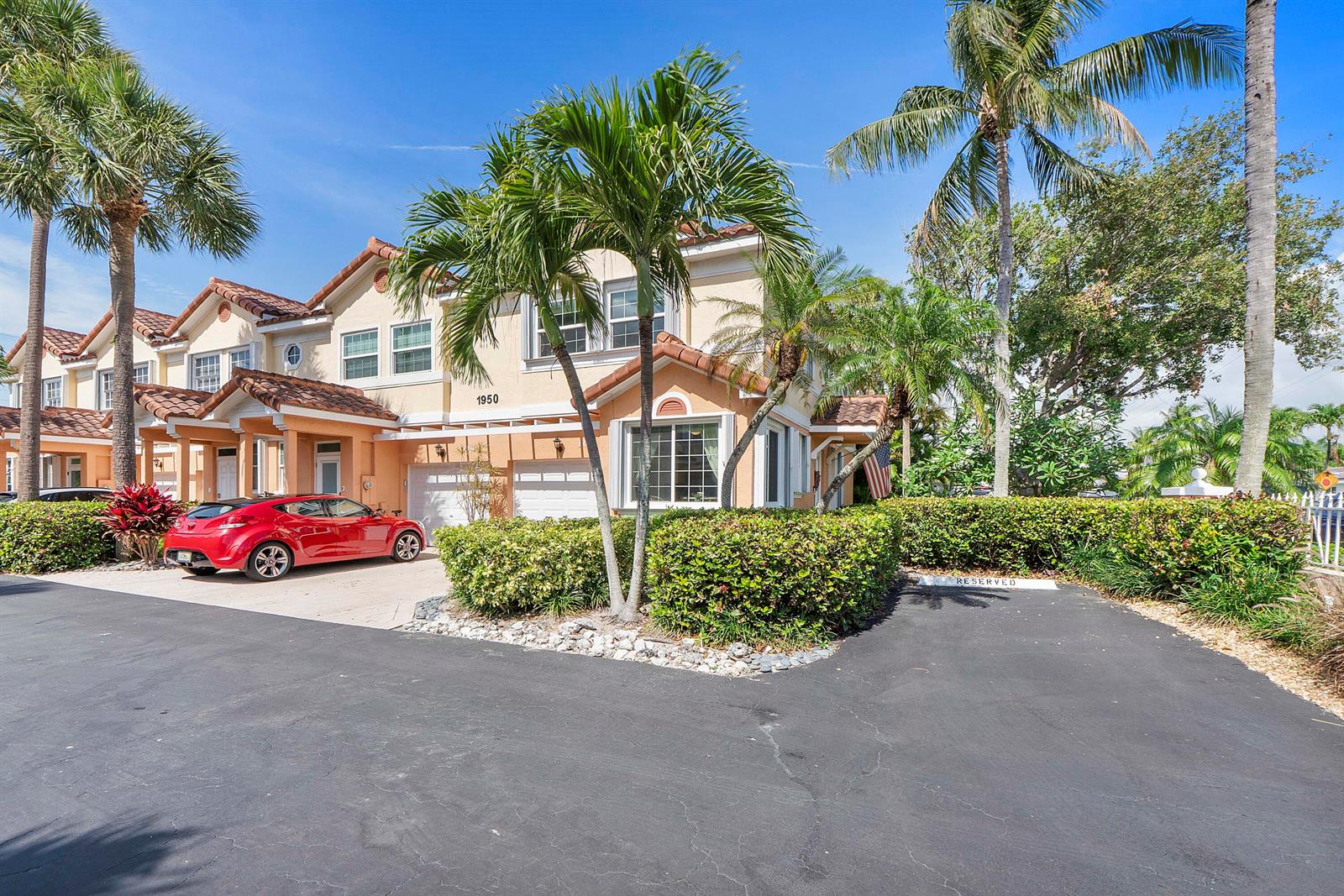A two-story townhouse with a red car parked in the driveway and palm trees — 1950 Ne 7th St # 105, Deerfield Beach FL 33441, DEERFIELD BEACH, FL