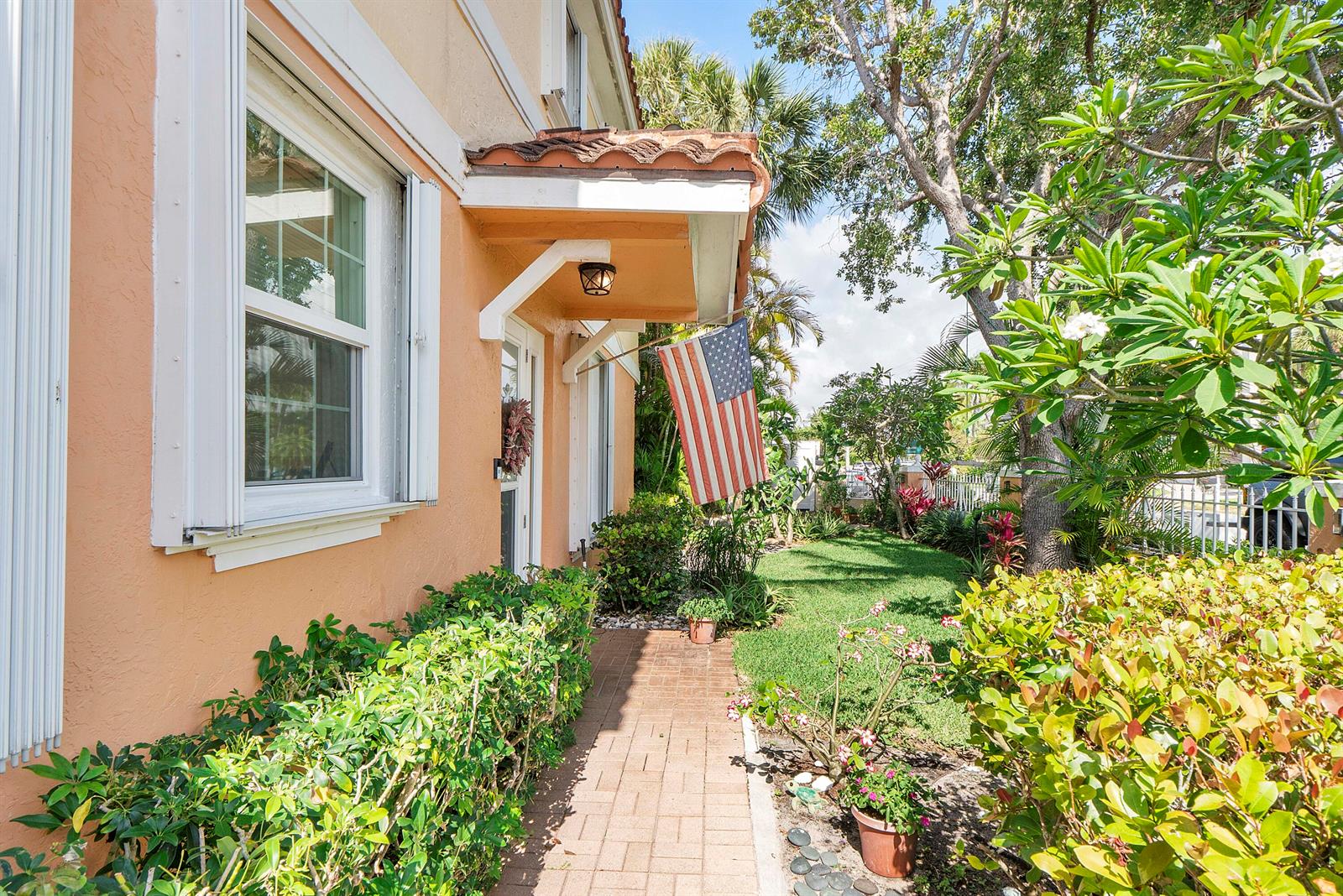 A brick walkway leads to the entrance of a peach-colored house with a tiled awning — 1950 Ne 7th St # 105, Deerfield Beach FL 33441, DEERFIELD BEACH, FL