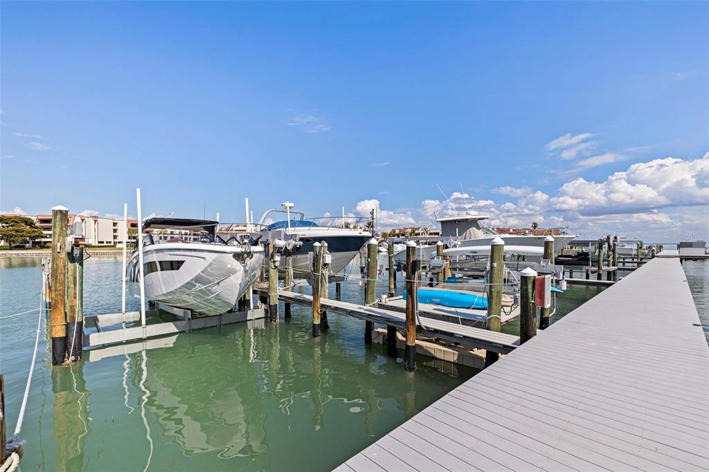A wooden boat dock with several boats moored in the water under a blue sky — 117 YACHT CLUB LANE, TIERRA VERDE, FL
