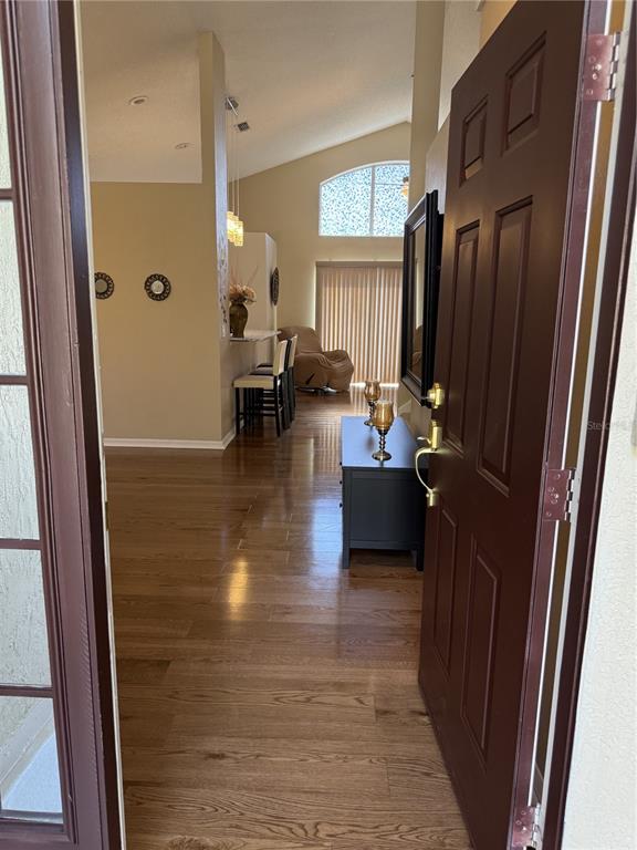 A view from an open doorway into a living area with hardwood floors and vaulted ceilings — 227 DILLON WAY, DAVENPORT, FL