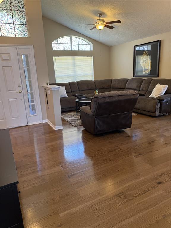 A living room features hardwood floors, a large sectional sofa, and a vaulted ceiling — 227 DILLON WAY, DAVENPORT, FL