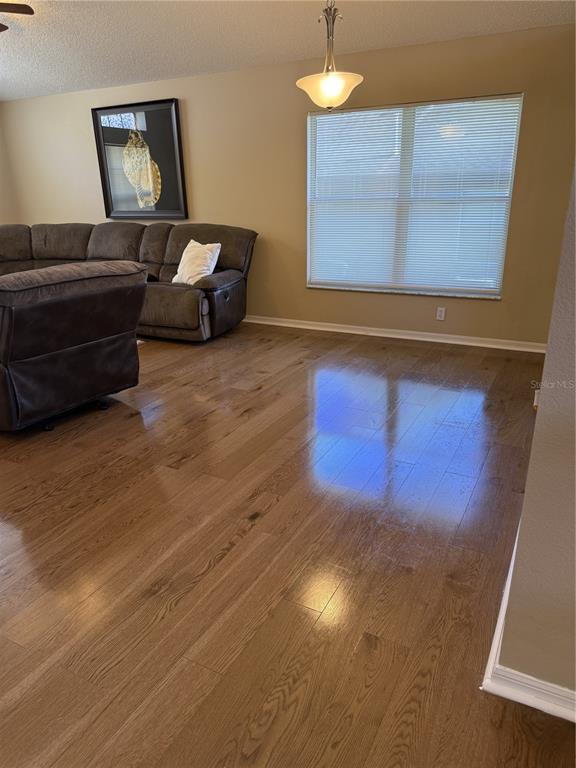 A living room features hardwood floors, a large sectional sofa, and a window with blinds — 227 DILLON WAY, DAVENPORT, FL