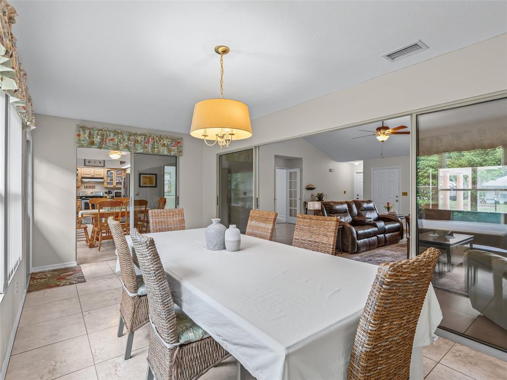 A dining room with a wicker chair set, a white tablecloth, and sliding glass doors — 11299 SE 175TH LANE, SUMMERFIELD, FL