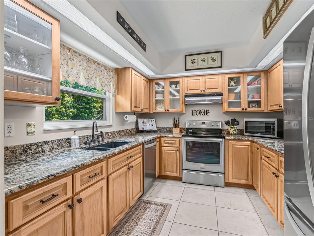 A kitchen features light wood cabinets, granite countertops, stainless steel appliances, and a window — 11299 SE 175TH LANE, SUMMERFIELD, FL