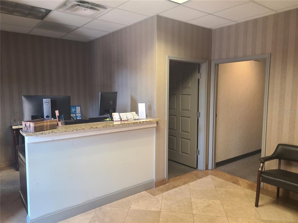 A reception area features a granite-topped desk, two doorways, and striped wallpaper — 483 MONTGOMERY PLACE, ALTAMONTE SPRINGS, FL