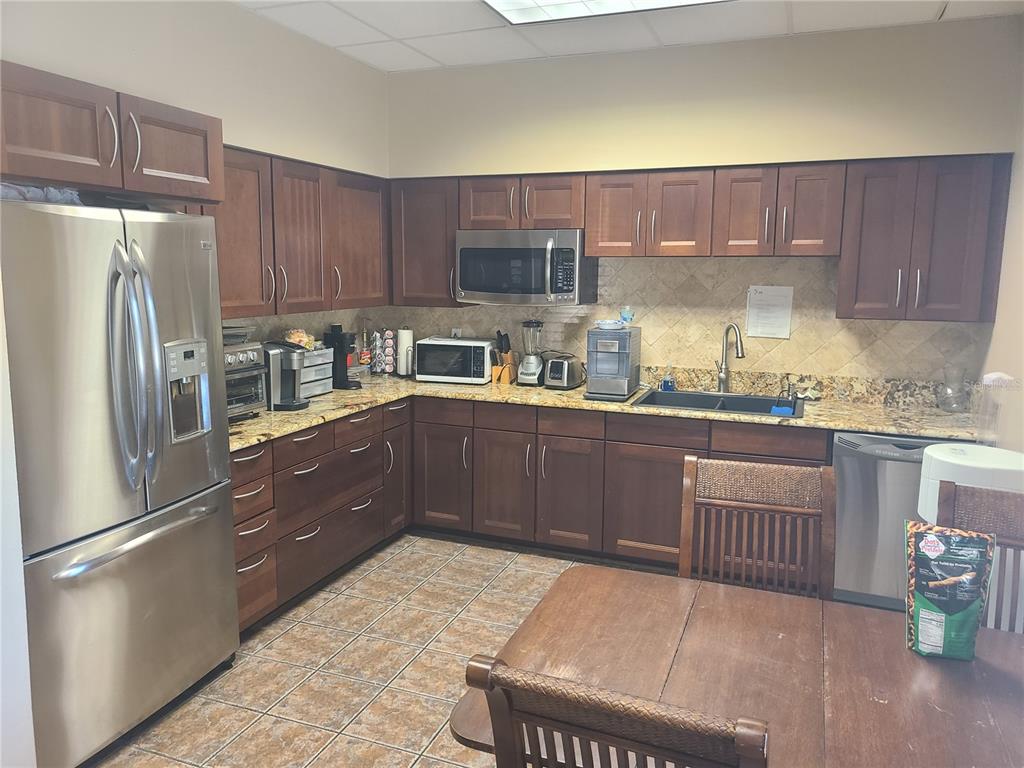 A kitchen with dark wood cabinets, granite countertops, stainless steel appliances, and tile flooring — 483 MONTGOMERY PLACE, ALTAMONTE SPRINGS, FL