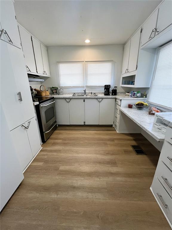 A kitchen features white cabinets, stainless steel appliances, light countertops, and wood-look flooring — 6916 MARLIN LANE, BRADENTON, FL